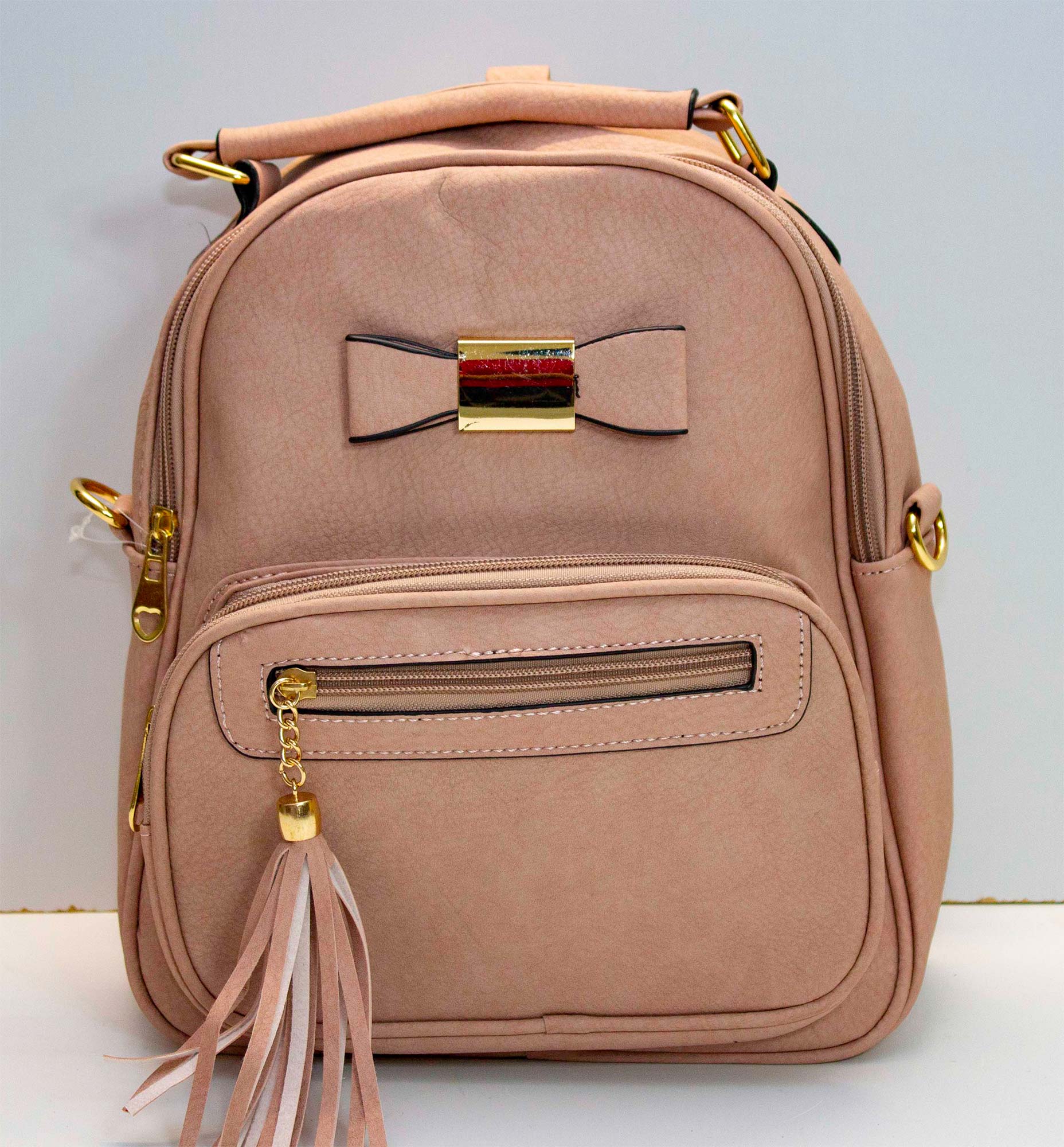 Mochila pequeña de cuero sintetico con forro, varios compartimentos, adorno de moño, correa para diferentes usos.