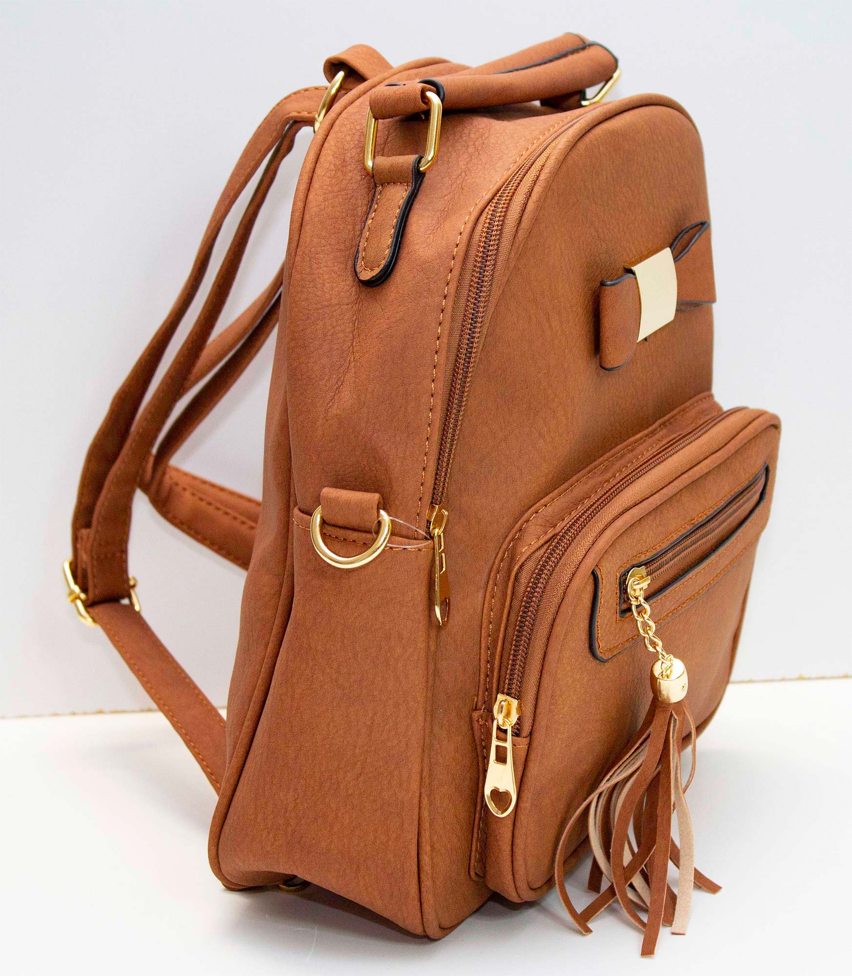 Mochila pequeña de cuero sintetico con forro, varios compartimentos, adorno de moño, correa para diferentes usos.