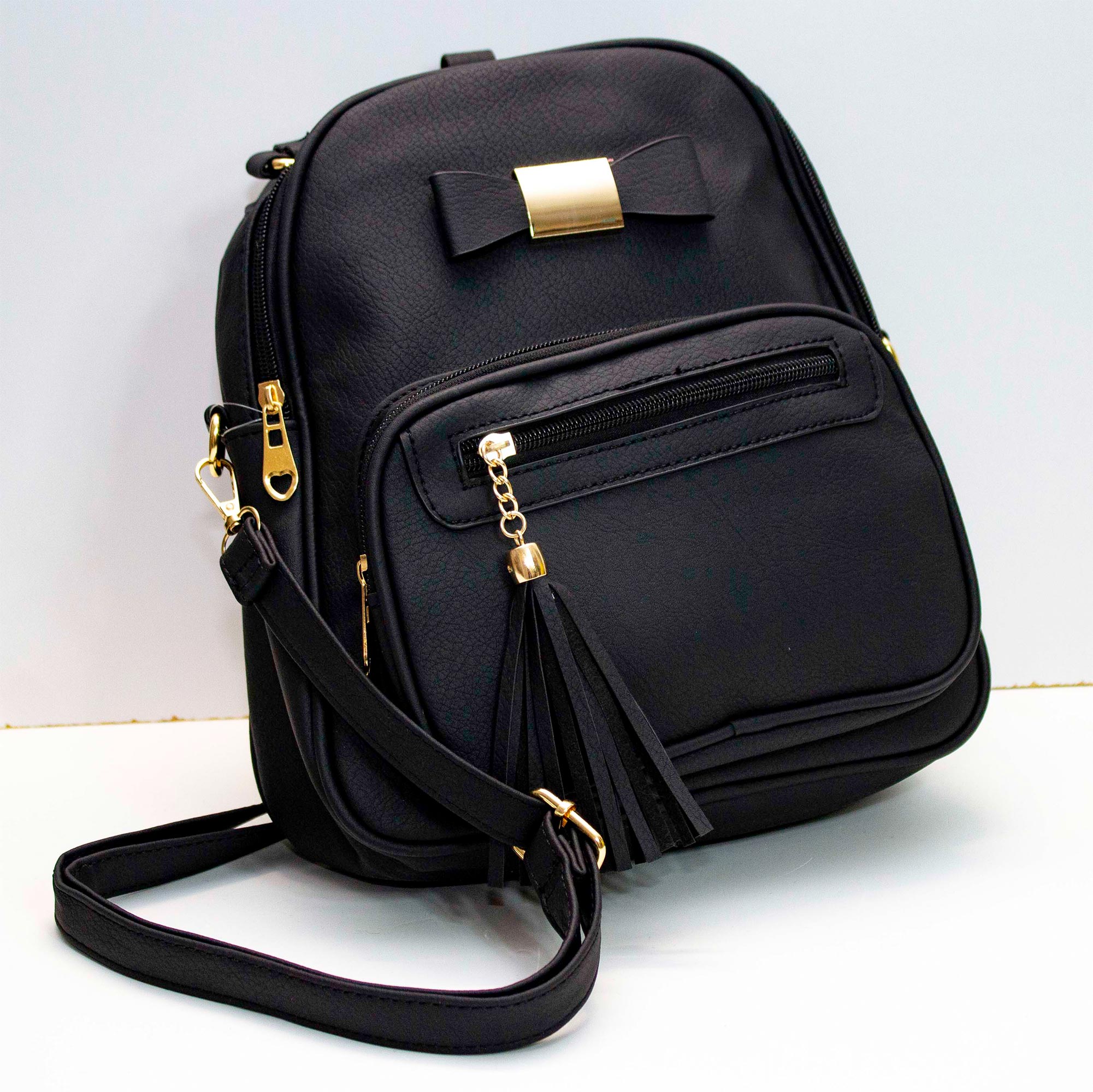 Mochila pequeña de cuero sintetico con forro, varios compartimentos, adorno de moño, correa para diferentes usos.