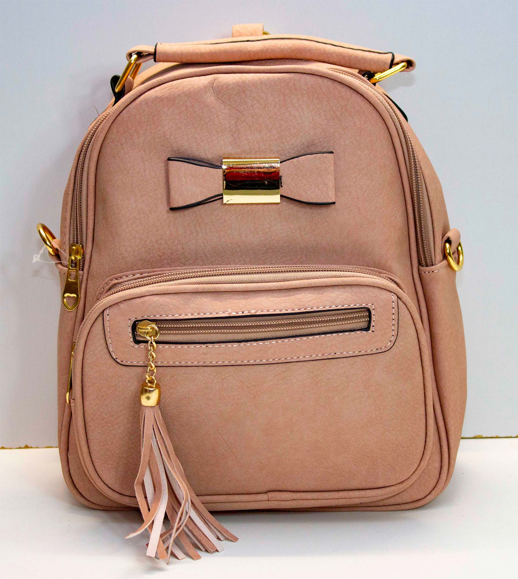 Mochila pequeña de cuero sintetico con forro, varios compartimentos, adorno de moño, correa para diferentes usos.