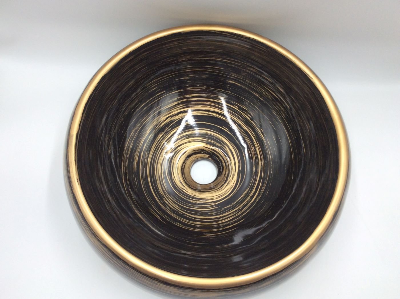 Lavabo Cerámico para Baño COZ- CO, forma circular color negro con detalles en tono cobrizo. De sobreponer, con diseño europeo ideal para todo tipo de baños. Dimensiones 40.0 x 40.0 x 14.5 cms. (base x altura x profundidad)