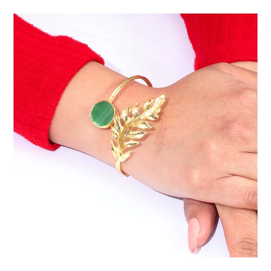 Brazalete con un diseño distintivo, con una punta esculpida con forma de hoja tipo guirnalda en un extremo, y en el otro extremo, una incrustación de piedra natural.