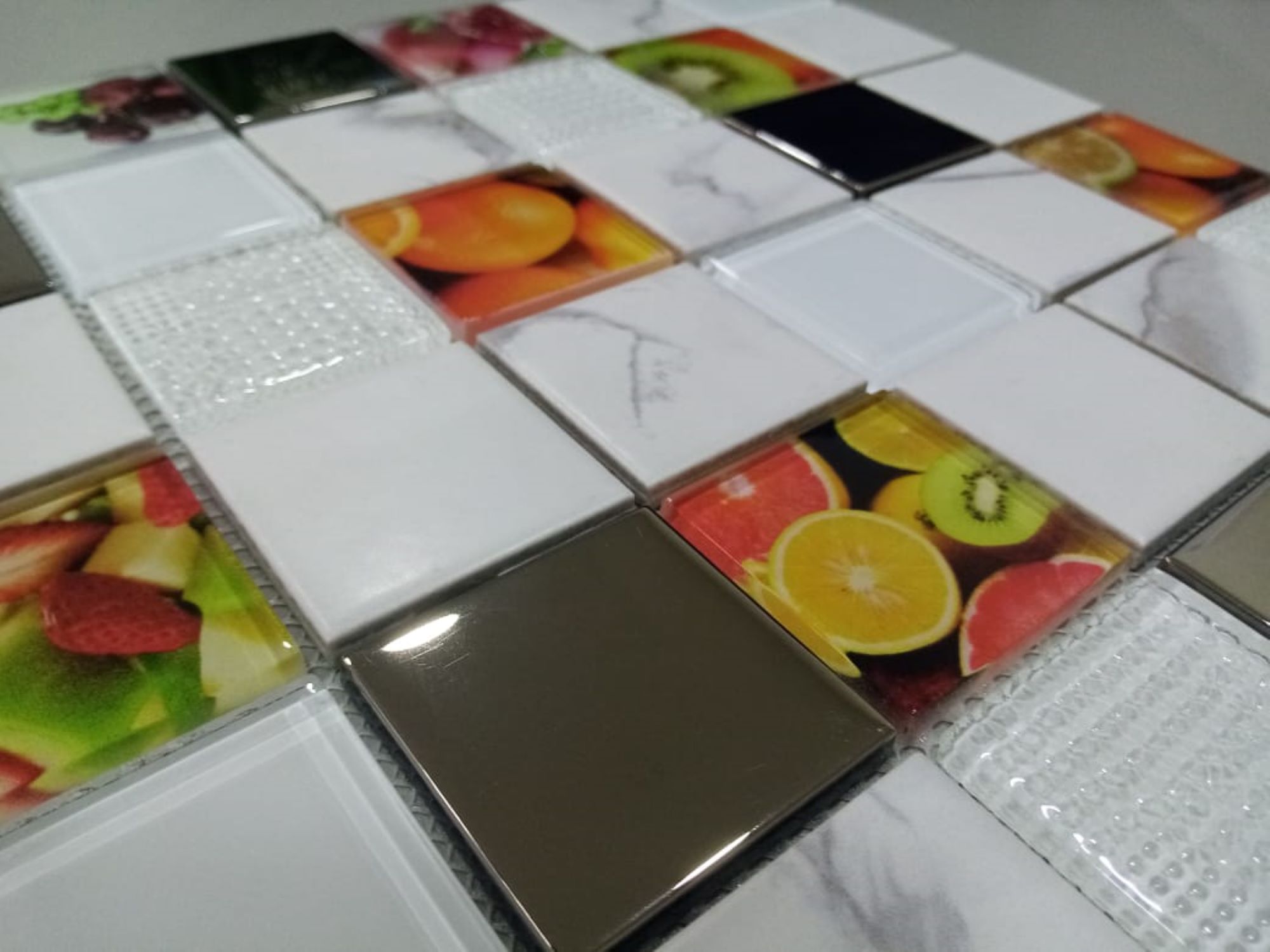Malla o Mosaico Decorativo de vidrio y metal FRU,  medida 30 x 30 cms. (base por altura). Diseño en color blanco marmoleado con imágenes de frutas y detalles en relieve. Caja de 5 piezas.